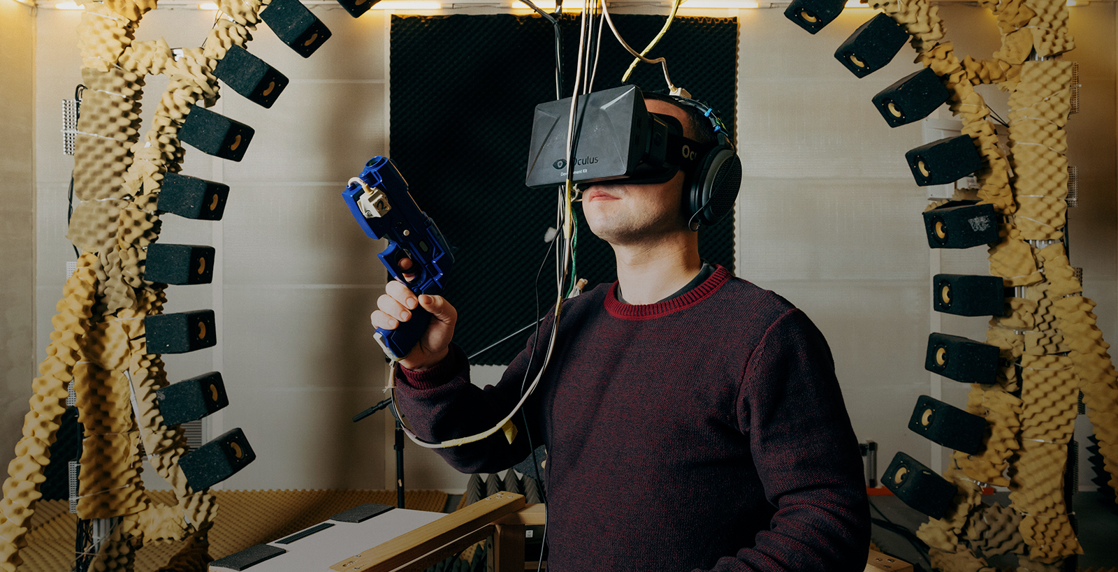 image of person with fake gun in hand and wearing a virtual headset with speakers behind him