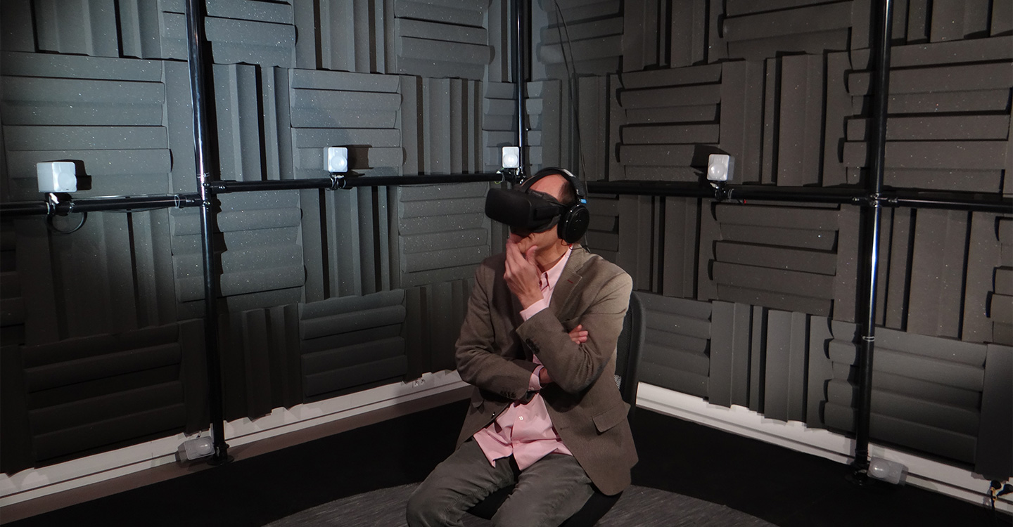 Man sitting in a room, wearing virtual headset, pink shirt being worn