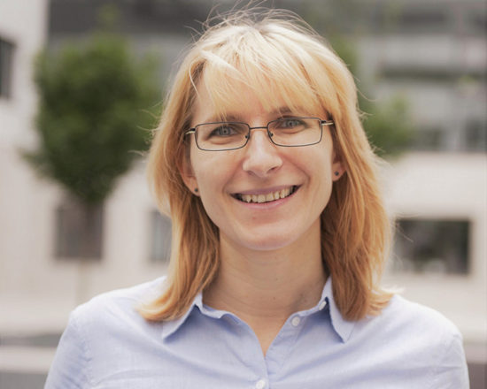 blonde woman with spectacles smiling at camera